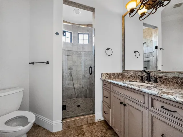a bathroom with a granite countertop sink a toilet and shower