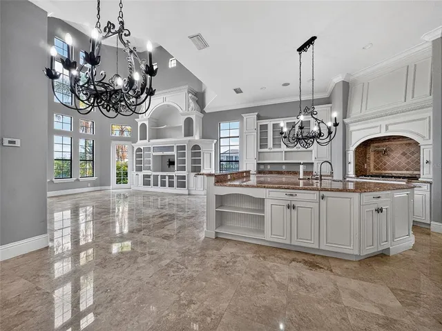 a kitchen with kitchen island granite countertop a white cabinets and chandelier