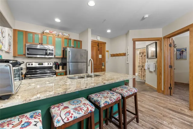 a kitchen with stainless steel appliances a dining table chairs and refrigerator