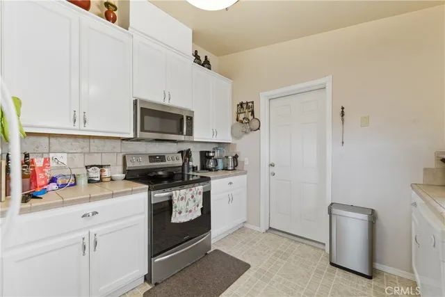 a kitchen with stainless steel appliances granite countertop a stove top oven a sink dishwasher and white cabinets with wooden floor