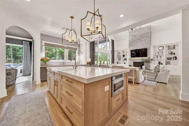a kitchen with kitchen island granite countertop a sink a counter top space a stove and a chandelier