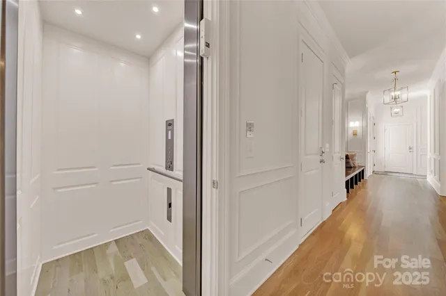 a view of a hallway with wooden floor and a bathroom