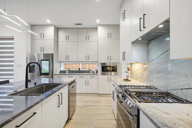 a kitchen with stainless steel appliances granite countertop a sink stove and cabinets