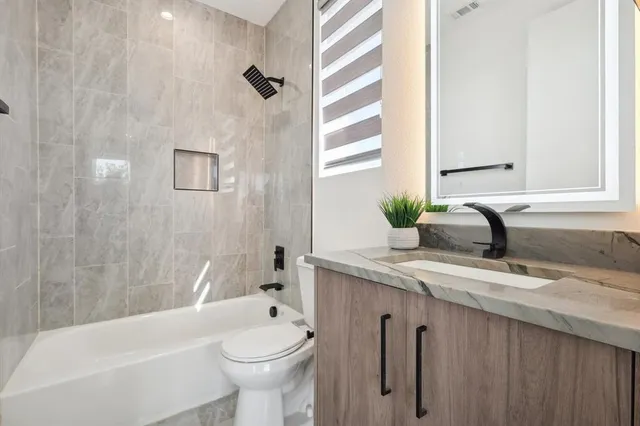 a bathroom with a granite countertop sink and a bathtub
