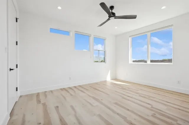 a view of empty room with wooden floor and fan