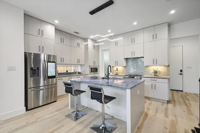 a kitchen with kitchen island granite countertop a sink stove and refrigerator