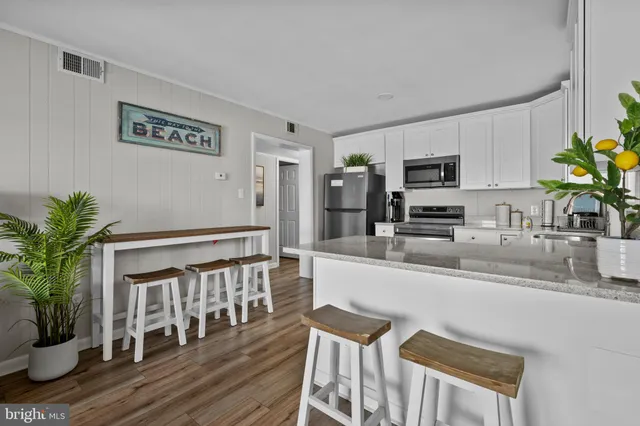 a kitchen with stainless steel appliances granite countertop a refrigerator a stove a sink a dining table and chairs with wooden floor