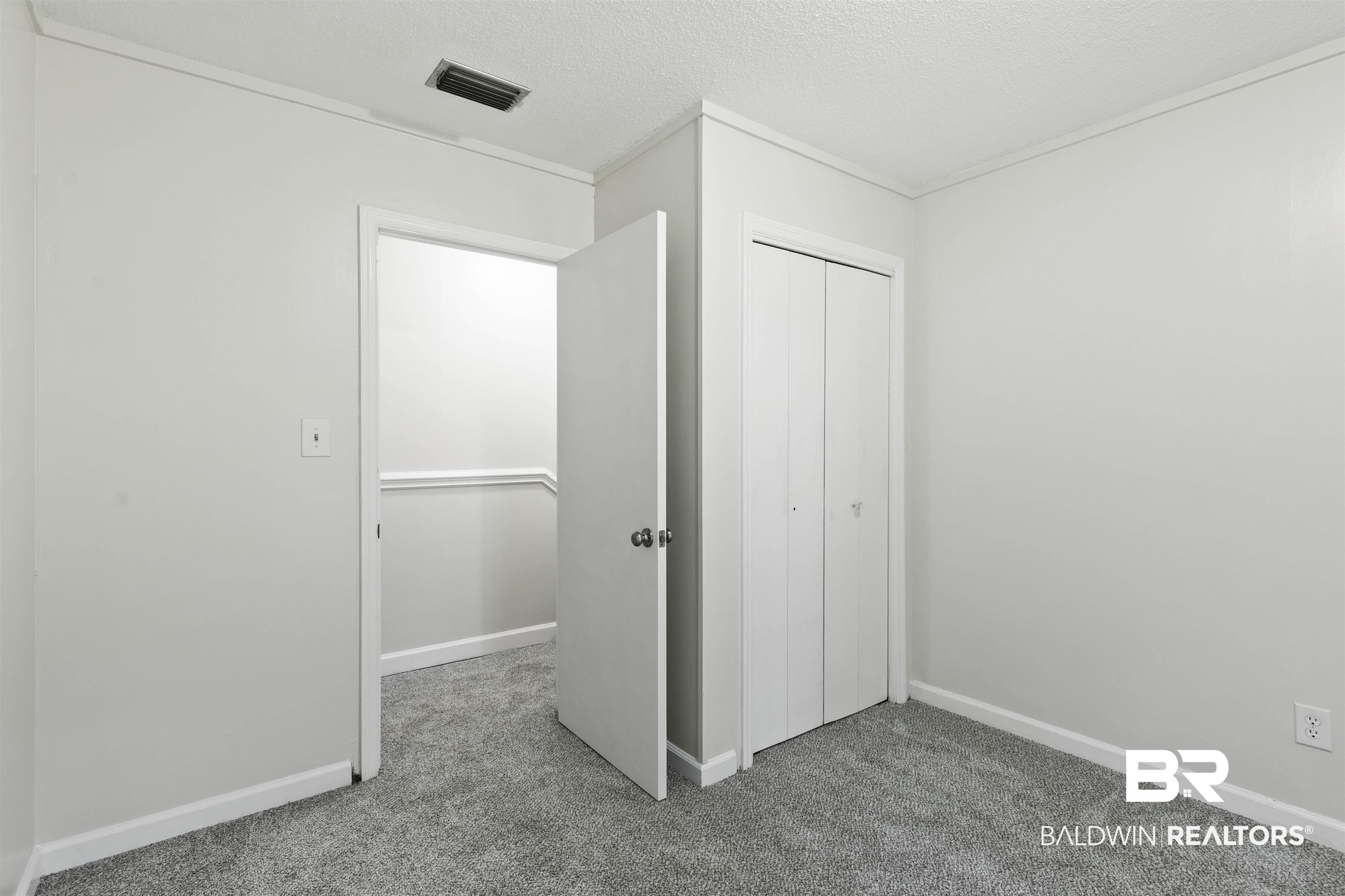 10420 Johnson Road South Mobile, AL 36695 - Photo 39 of 75 Neutral-toned room with plush gray carpet, clean white walls, and a recessed closet featuring bifold doors