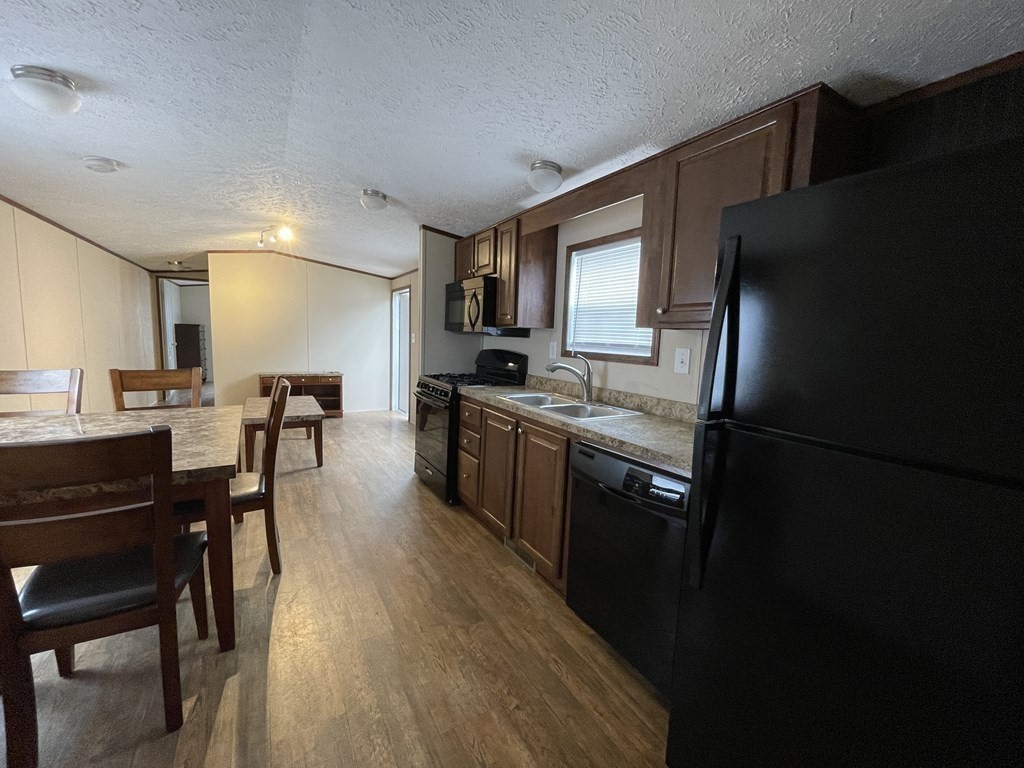 268 Palmer Road, Unit 23 Monson, MA 01057 - Photo 12 of 18 a kitchen with stainless steel appliances granite countertop a refrigerator a stove a sink dishwasher a dining table and chairs with wooden floor