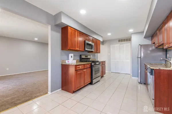 a kitchen with stainless steel appliances granite countertop a stove a sink and a microwave