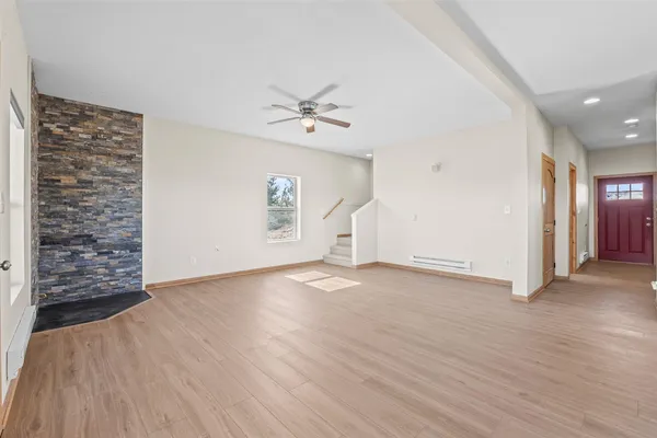 an empty room with wooden floor chandelier fan and windows
