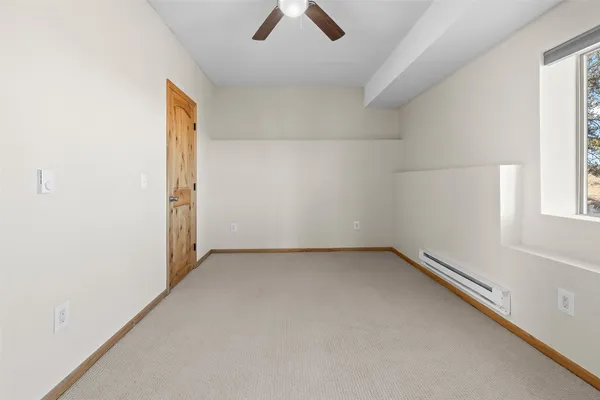 an empty room with ceiling fan and window