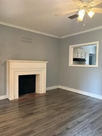 a view of an empty room with wooden floor fireplace and a window