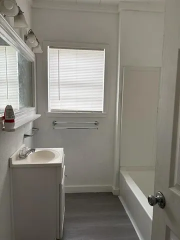 a bathroom with a sink a bathtub and next to a window