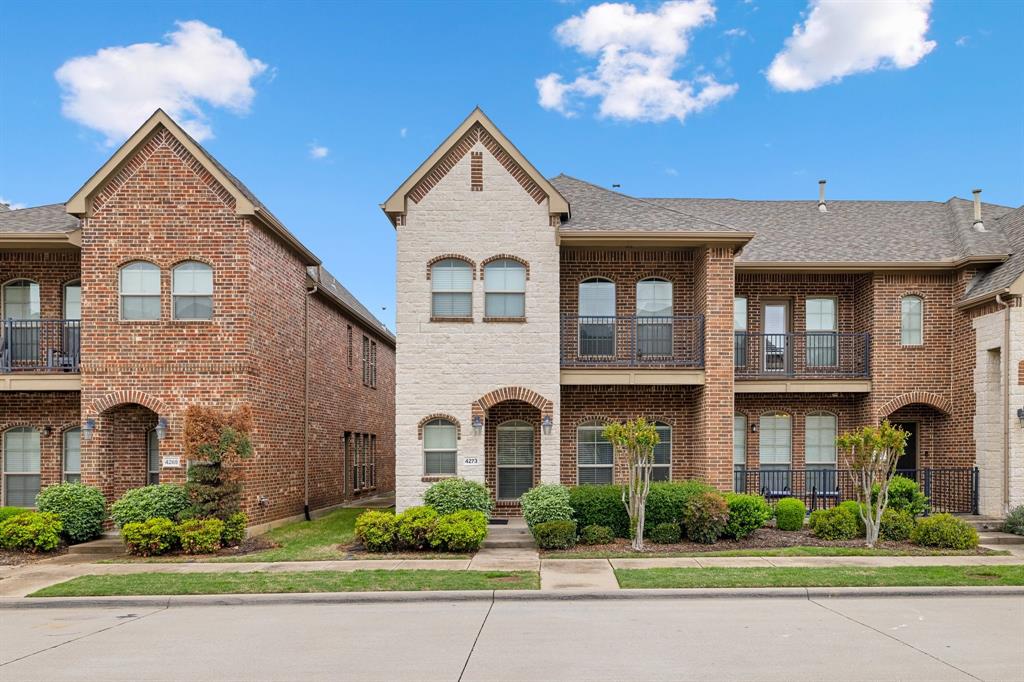 View of property with brick siding and roof with shingles