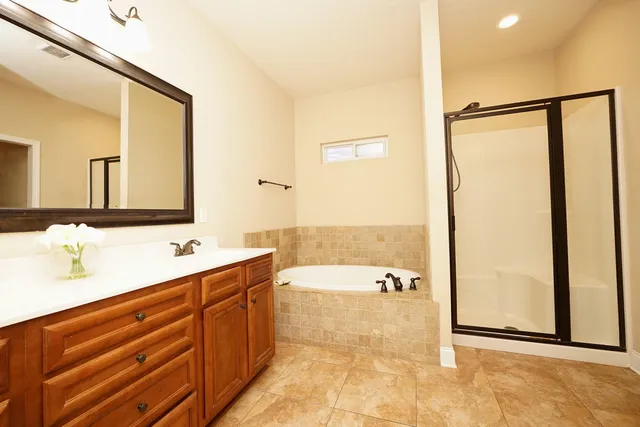 a spacious bathroom with a double vanity sink a mirror and a bathtub