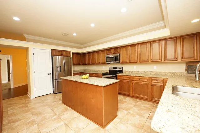 a kitchen with stainless steel appliances granite countertop a stove top oven a refrigerator a sink and dishwasher with wooden cabinets