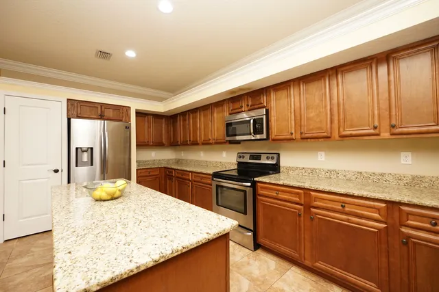 a kitchen with stainless steel appliances granite countertop wooden cabinets a stove top oven a granite counter top and a sink