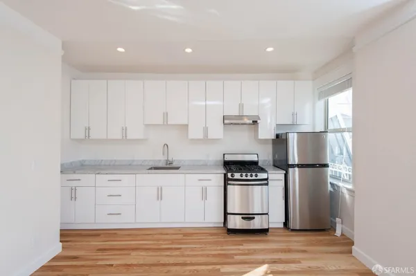 a kitchen with cabinets stainless steel appliances and wooden floor