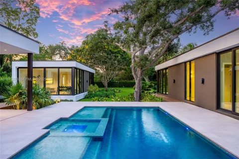 a backyard of a house with plants and large tree
