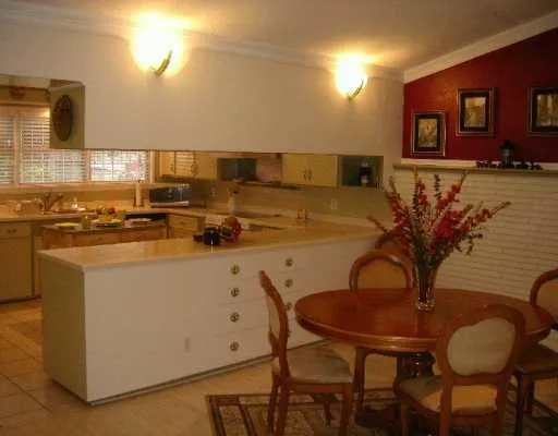 a kitchen with stainless steel appliances granite countertop a sink a stove a dining table and chairs