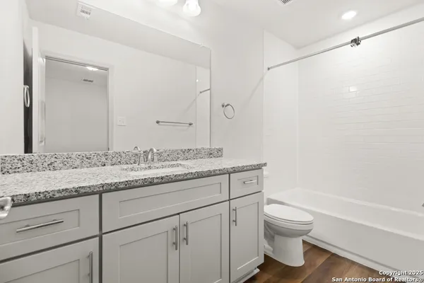 a bathroom with a granite countertop sink a toilet and a bathtub