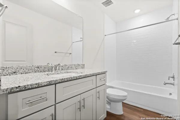 a bathroom with a granite countertop sink a toilet and bathtub