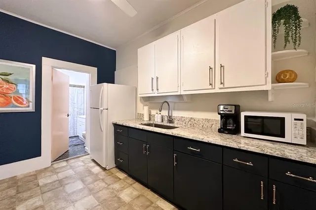a kitchen with granite countertop a sink a stove and refrigerator