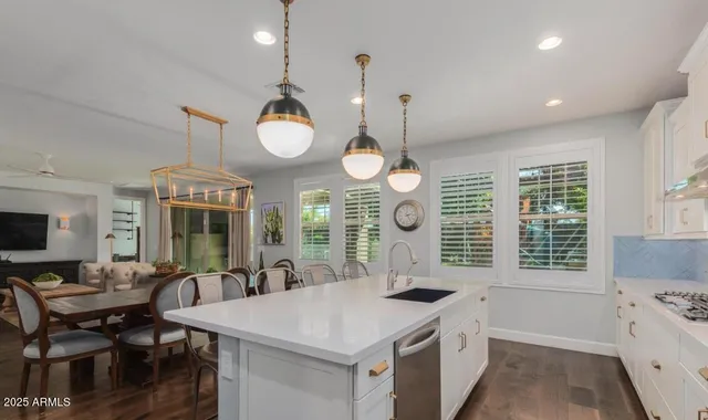 a kitchen with cabinets a sink appliances and chairs