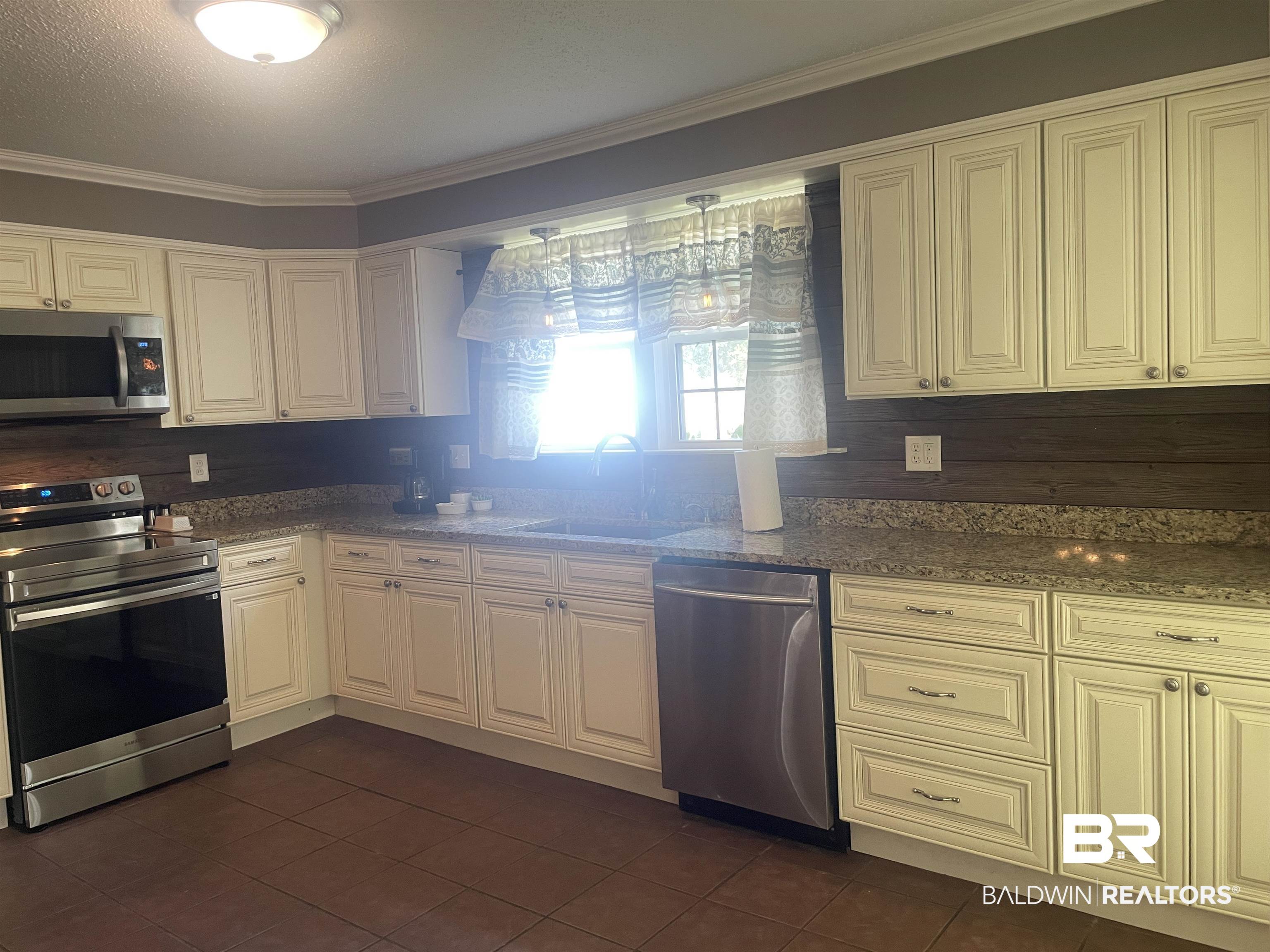 13850 Celeste Road Chunchula, AL 36521 - Photo 12 of 29 Kitchen with appliances with stainless steel finishes, crown molding, dark stone countertops, dark tile patterned floors, and a textured ceiling