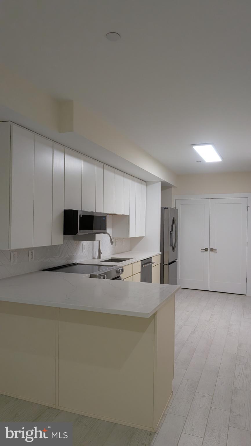 329 16th Street Southeast, Unit 1 Washington, DC 20003 - Photo 17 of 22 a kitchen with stainless steel appliances granite countertop a sink a stove a refrigerator a microwave and cabinets