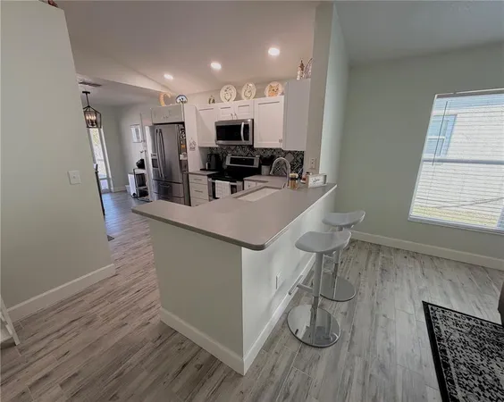 a kitchen with stainless steel appliances granite countertop a refrigerator a stove and a wooden floors