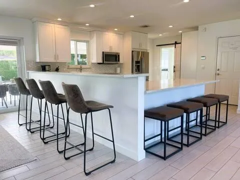a kitchen with stainless steel appliances kitchen island granite countertop a table chairs and a refrigerator