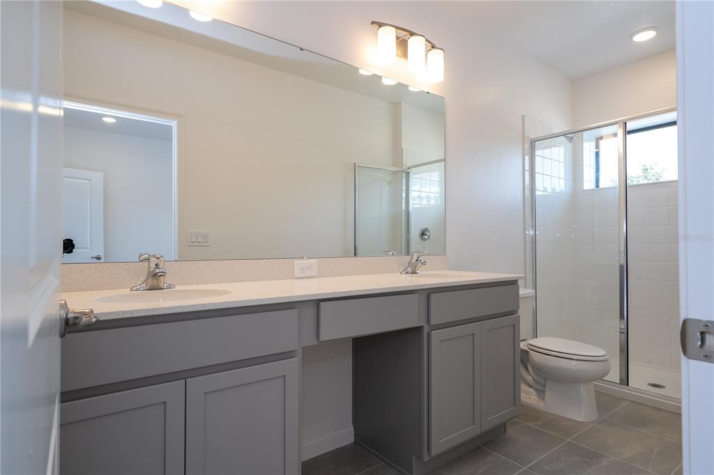 10592 Ebb Tide Lane Orlando, FL 32821 - Photo 61 of 85 a bathroom with a double vanity sink toilet and a mirror