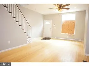 a view of an empty room and window with a ceiling fan