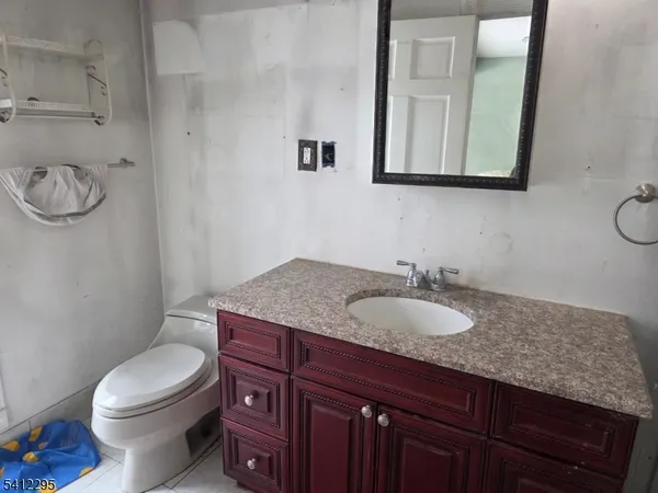 a bathroom with a granite countertop toilet sink and mirror