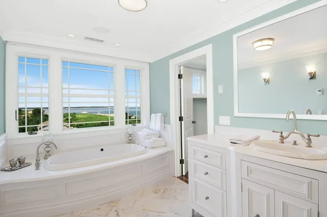 a bathroom with a tub sink double vanity and a mirror