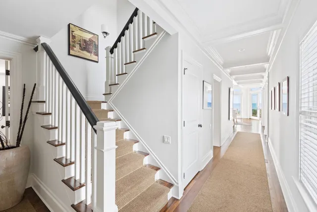 a view of staircase with lots of frames on wall and a view of a front door