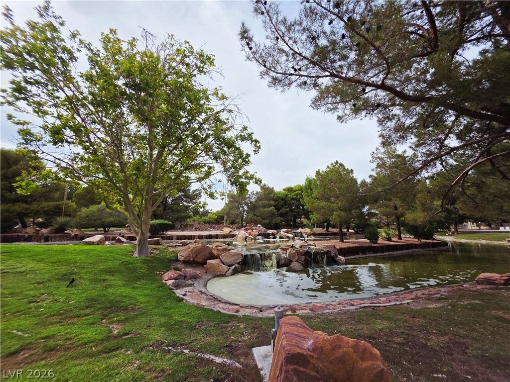 2920 Setting Sun Street Las Vegas, NV 89117 - Photo 8 of 43 Lush landscaping and a tranquil pond with a waterfall create a serene outdoor retreat.