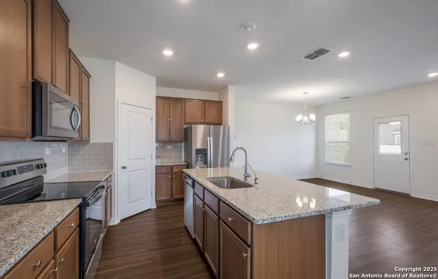 a kitchen with stainless steel appliances granite countertop a kitchen island a stove a refrigerator and a sink