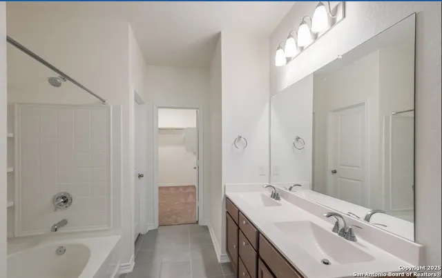 a bathroom with a tub sink double vanity and a mirror