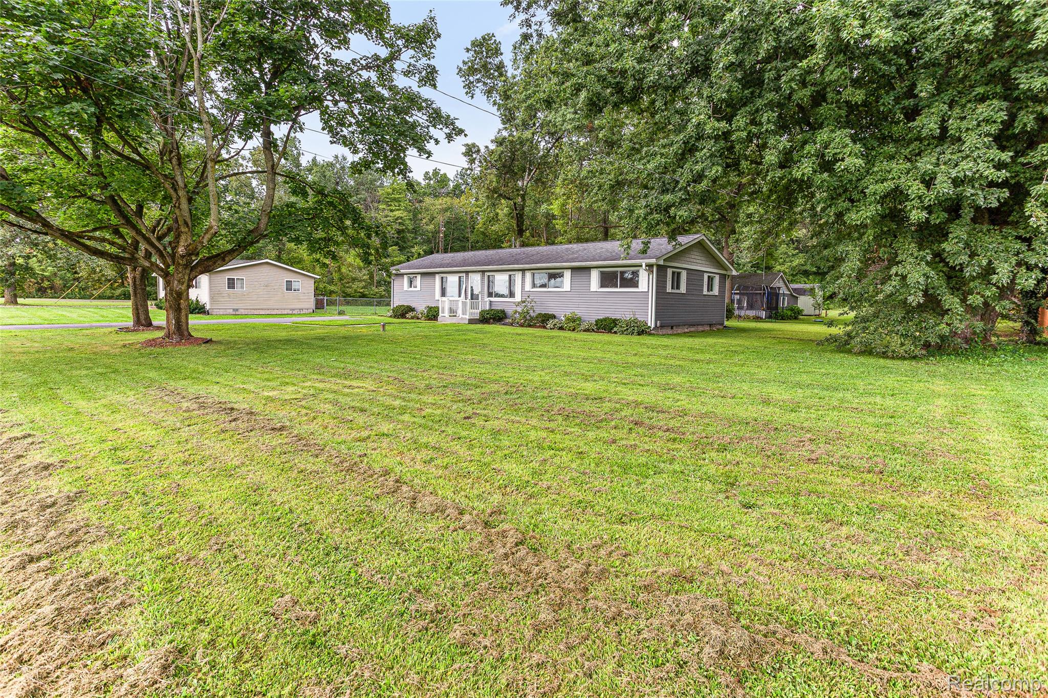 9561 Exeter Road Carleton, MI 48117 - Photo 37 of 46 Expansive green lawn with mature trees and a gray-sided home