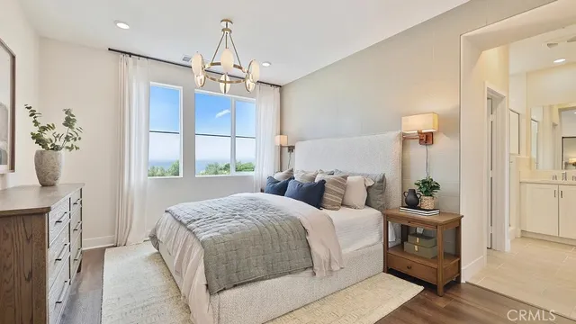 a bedroom with a bed a chandelier and dresser