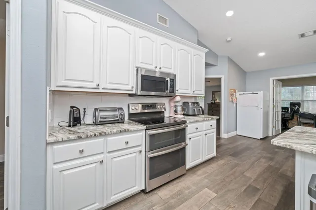 a kitchen with white cabinets and stainless steel appliances
