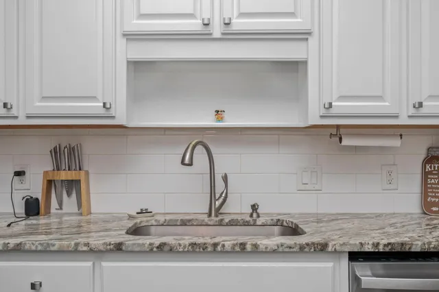 a kitchen with granite countertop white cabinets and a sink