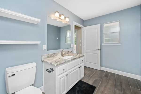 a bathroom with a granite countertop sink a toilet and a mirror