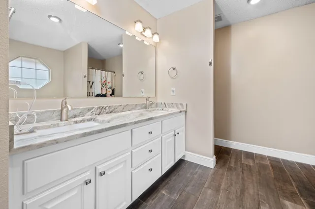 a bathroom with a granite countertop sink mirror and cabinets