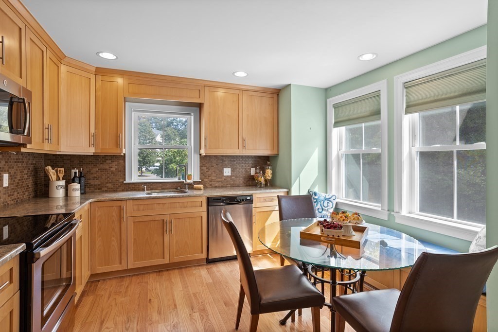 8 High Street, Unit D2 Acton, MA 01720 - Photo 10 of 35 a kitchen with stainless steel appliances granite countertop a stove top oven a sink dishwasher a dining table and chairs with wooden floor