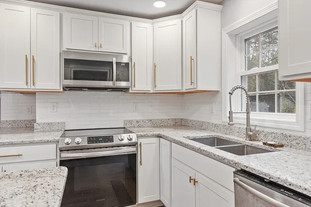a kitchen with stainless steel appliances granite countertop a sink stove and microwave