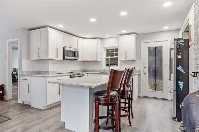 a kitchen with stainless steel appliances granite countertop a white cabinets and a stove top oven